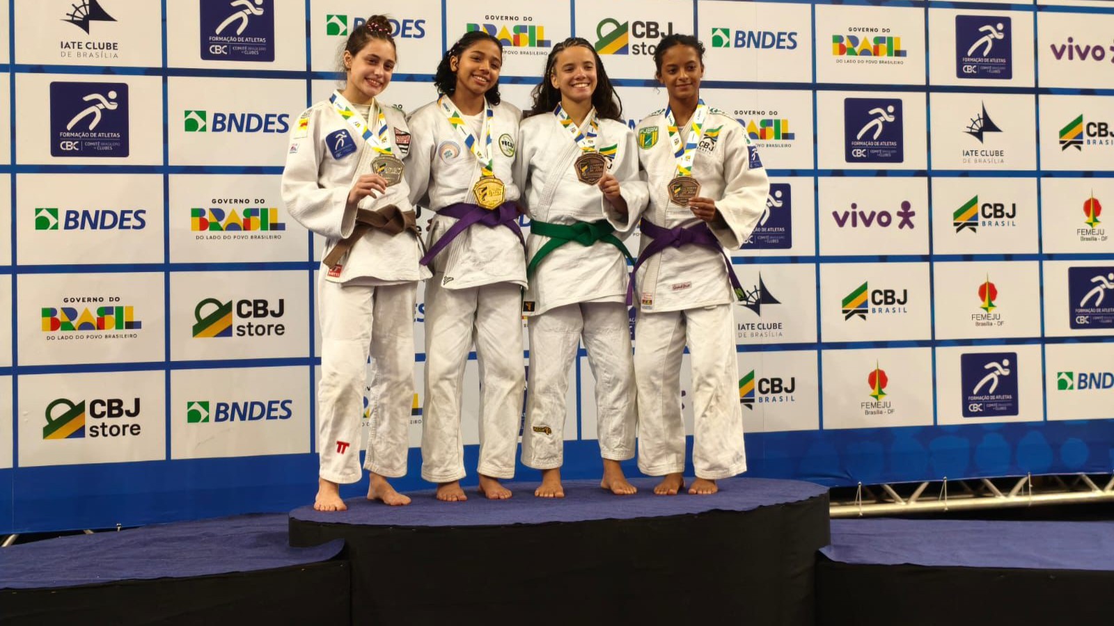 grupo de atletas vestidas de kimono em um pódio